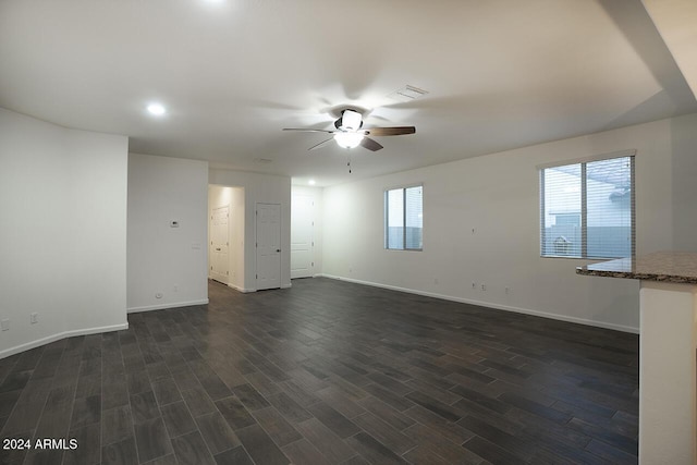 unfurnished room with a healthy amount of sunlight, ceiling fan, and dark wood-type flooring