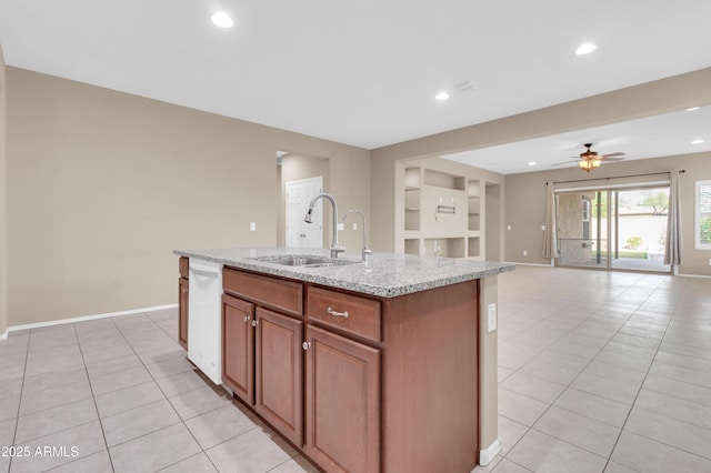 kitchen with light tile patterned floors, baseboards, a kitchen island with sink, built in shelves, and a sink