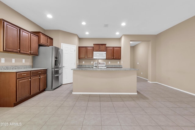 kitchen featuring a center island with sink, recessed lighting, white microwave, range, and stainless steel fridge with ice dispenser