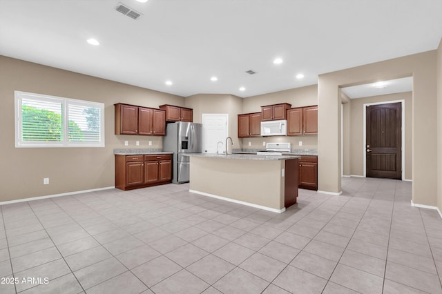 kitchen featuring an island with sink, white appliances, baseboards, and recessed lighting