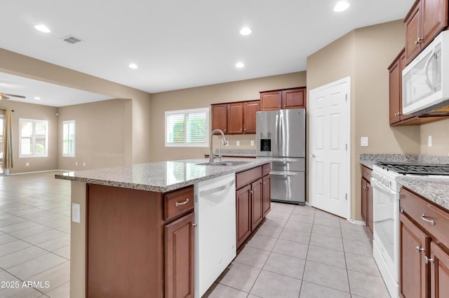 kitchen with white appliances, a center island with sink, a sink, and light tile patterned flooring