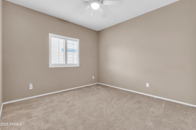 carpeted spare room featuring ceiling fan and baseboards