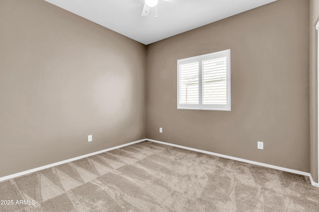 carpeted spare room featuring a ceiling fan and baseboards