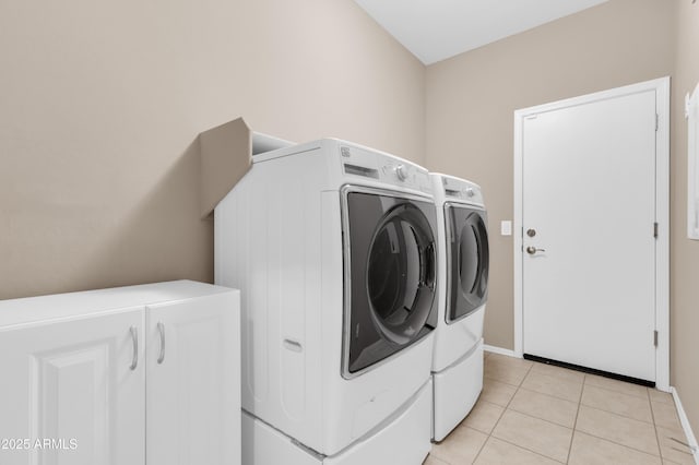 laundry area featuring light tile patterned floors, laundry area, washing machine and clothes dryer, and baseboards