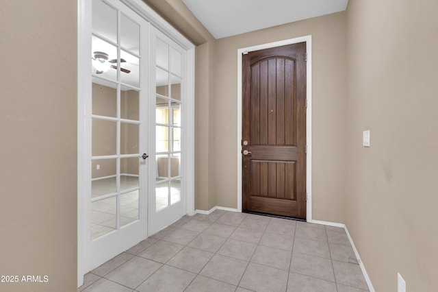 foyer entrance featuring french doors, light tile patterned flooring, and baseboards