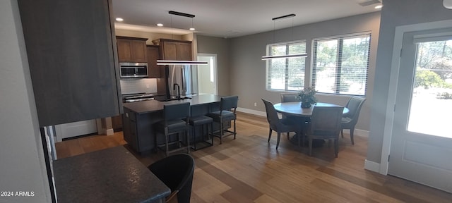 kitchen featuring decorative backsplash, a kitchen island with sink, dark hardwood / wood-style floors, hanging light fixtures, and a breakfast bar area