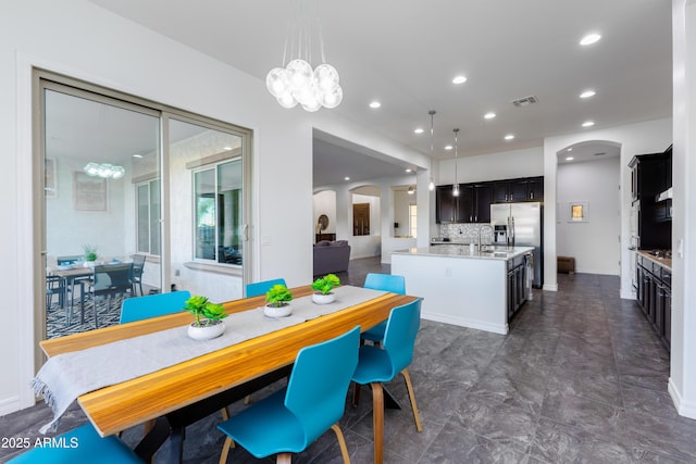 dining room with baseboards, visible vents, arched walkways, a notable chandelier, and recessed lighting