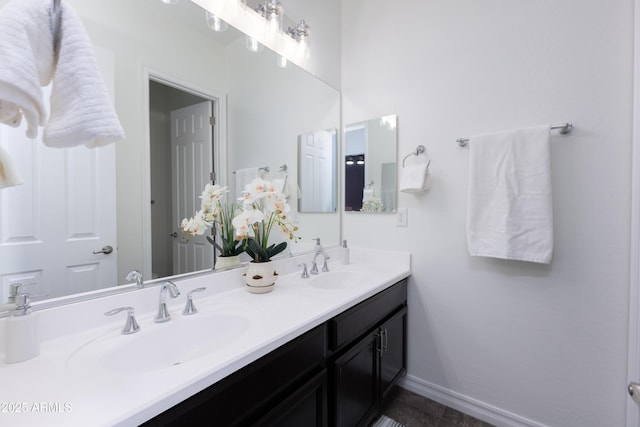 full bathroom with a sink, baseboards, and double vanity