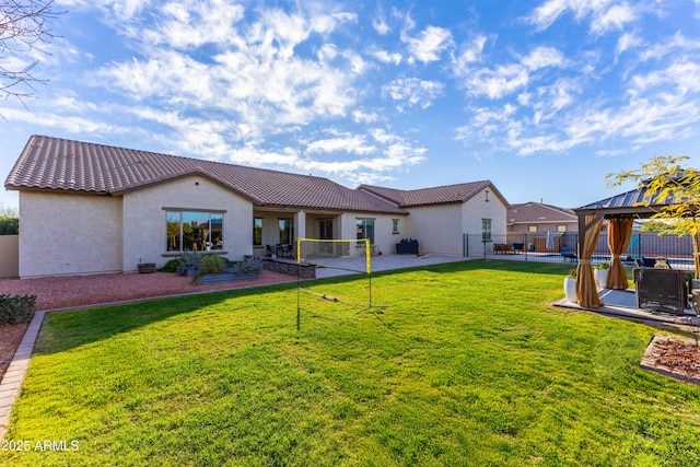 back of house with a gazebo, a tile roof, fence, and stucco siding