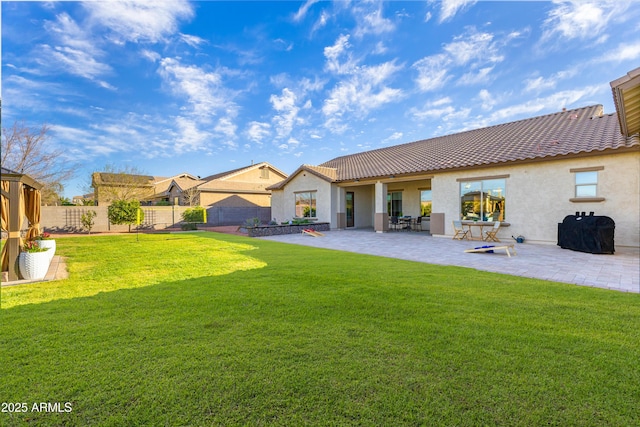 back of house featuring stucco siding, a tile roof, a fenced backyard, and a yard