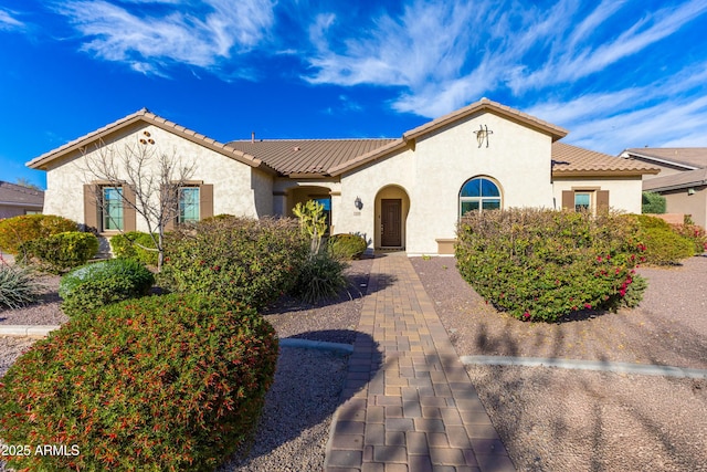 mediterranean / spanish home featuring a tiled roof and stucco siding