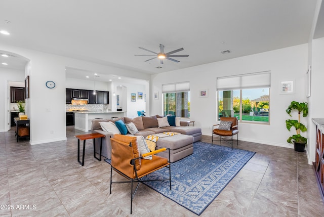 living area featuring visible vents, arched walkways, ceiling fan, and baseboards