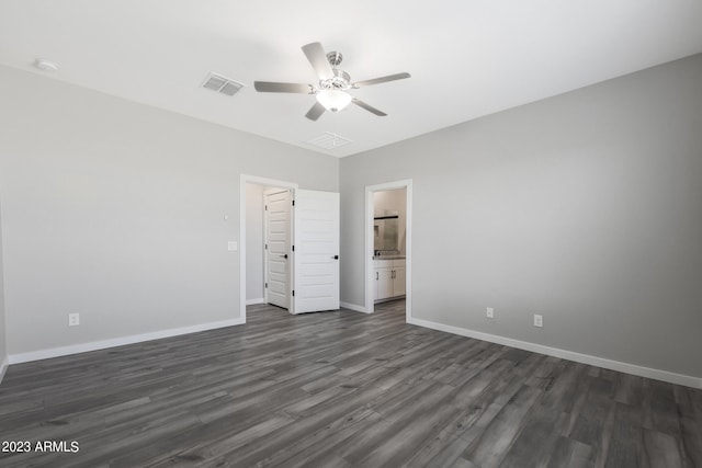 unfurnished bedroom with ceiling fan, ensuite bathroom, and dark wood-type flooring