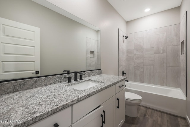 full bathroom with hardwood / wood-style floors, tiled shower / bath combo, toilet, and vanity