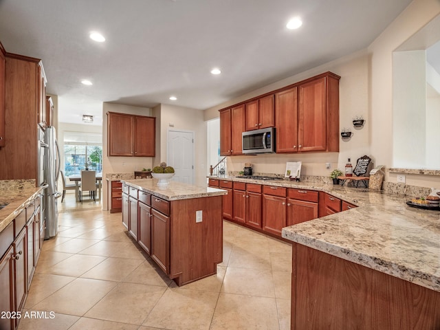 kitchen featuring light stone counters, kitchen peninsula, appliances with stainless steel finishes, and light tile patterned flooring