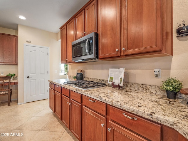 kitchen featuring stainless steel appliances, light stone countertops, and light tile patterned floors