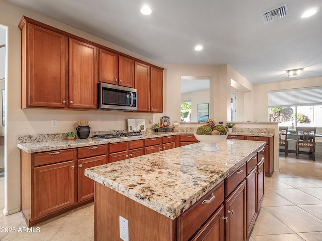 kitchen featuring stainless steel appliances, light stone counters, and a kitchen island