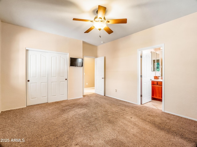 unfurnished bedroom featuring ensuite bathroom, light colored carpet, ceiling fan, and a closet