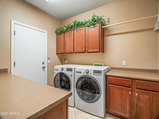 laundry room with washer and dryer, cabinets, light tile patterned flooring, and a textured ceiling