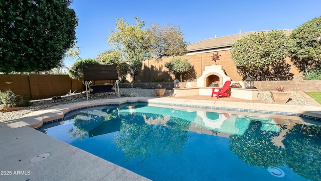 view of swimming pool featuring exterior fireplace