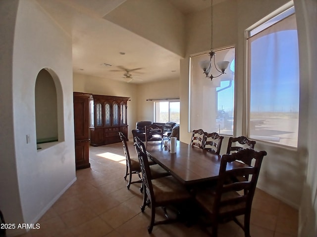 tiled dining space with ceiling fan with notable chandelier