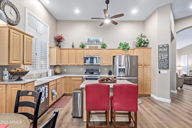 kitchen with sink, stainless steel appliances, plenty of natural light, light hardwood / wood-style floors, and light brown cabinetry