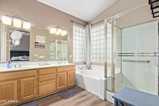 bathroom featuring wood-type flooring, vanity, shower with separate bathtub, and vaulted ceiling