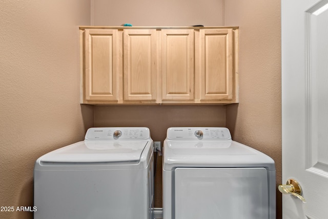 laundry area featuring washer and clothes dryer and cabinets