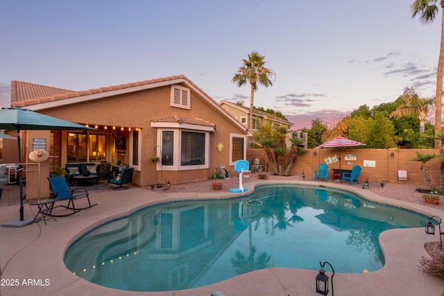 pool at dusk with a patio area and an outdoor living space