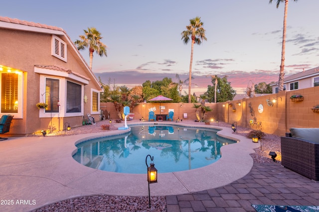 pool at dusk featuring a patio area