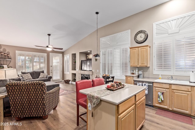 kitchen featuring dishwasher, light brown cabinets, a center island, sink, and decorative light fixtures