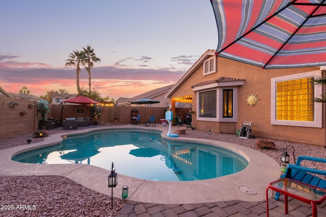 pool at dusk with a patio area