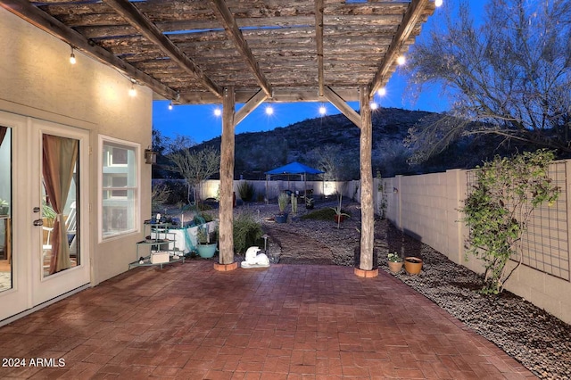 patio terrace at night featuring a mountain view and a pergola