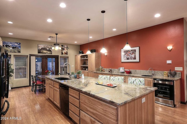 kitchen with an island with sink, french doors, beverage cooler, light hardwood / wood-style flooring, and light stone counters