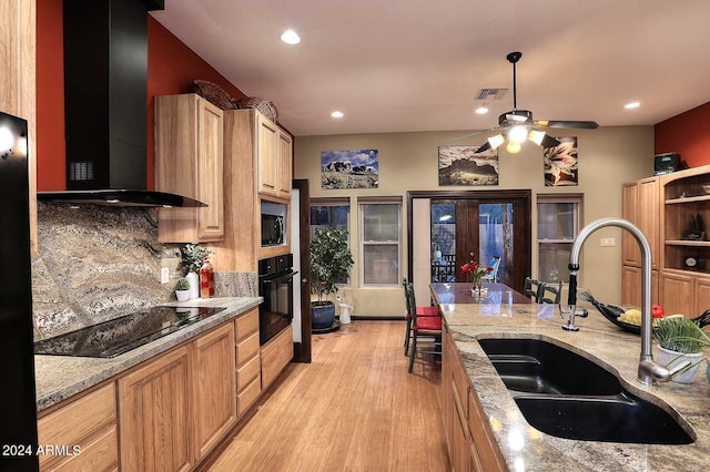 kitchen featuring ceiling fan, sink, light hardwood / wood-style floors, black appliances, and wall chimney range hood