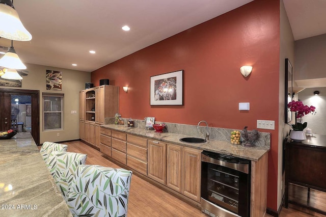 kitchen featuring pendant lighting, sink, light stone counters, light hardwood / wood-style floors, and beverage cooler