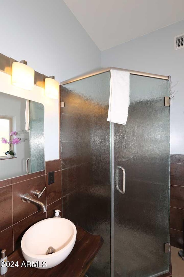 bathroom featuring tile walls, sink, and a shower with shower door