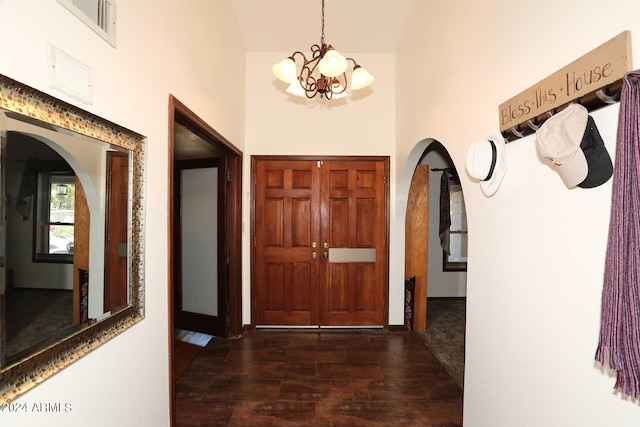 entryway with a notable chandelier, dark hardwood / wood-style floors, and a towering ceiling