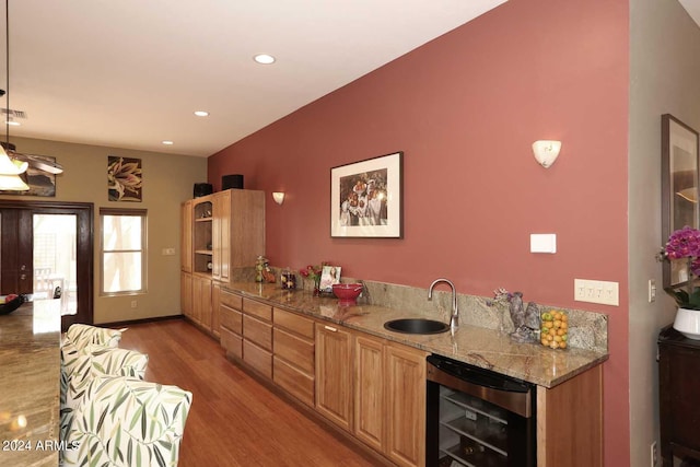 kitchen featuring wine cooler, hanging light fixtures, light stone counters, and sink