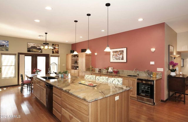 kitchen with hanging light fixtures, wine cooler, a center island with sink, and dark hardwood / wood-style flooring