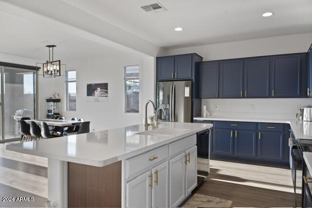 kitchen featuring pendant lighting, electric stove, stainless steel fridge, a kitchen island with sink, and black dishwasher