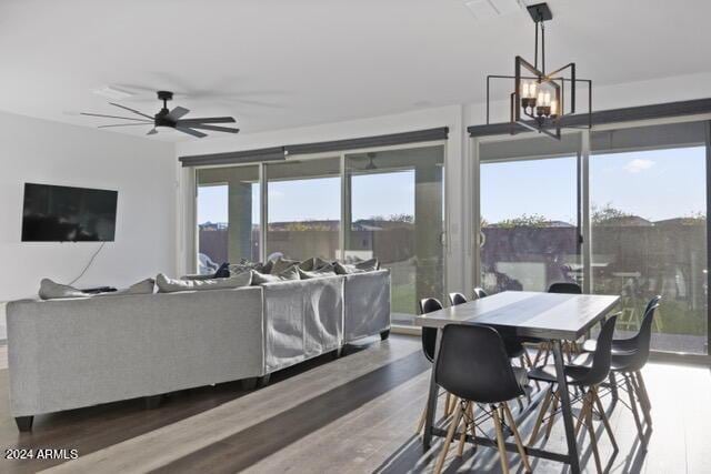 living room with ceiling fan with notable chandelier, a healthy amount of sunlight, and dark wood-type flooring