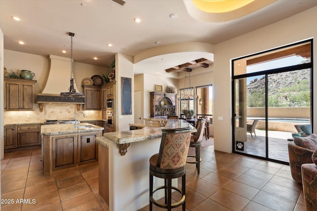 7731 E Soaring Eagle Way, Scottsdale, AZ 85266 - kitchen featuring a large island with sink, recessed lighting, backsplash, brown cabinets, and tile patterned flooring