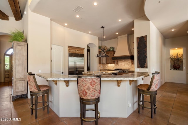 7731 E Soaring Eagle Way, Scottsdale, AZ 85266 - kitchen with built in refrigerator, custom exhaust hood, arched walkways, tasteful backsplash, and recessed lighting