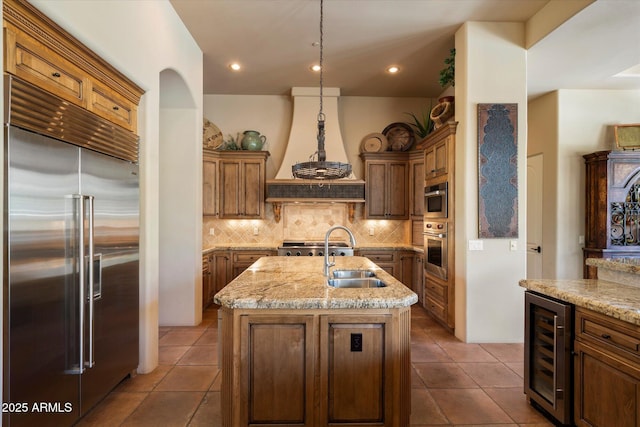 7731 E Soaring Eagle Way, Scottsdale, AZ 85266 - kitchen with stainless steel appliances, wine cooler, a kitchen island with sink, tasteful backsplash, and dark tile patterned flooring