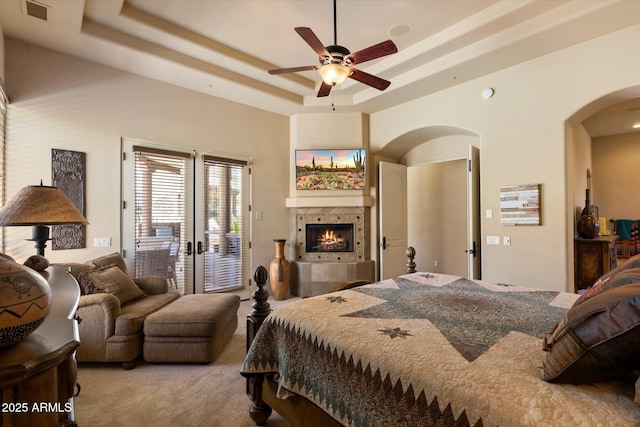 7731 E Soaring Eagle Way, Scottsdale, AZ 85266 - carpeted bedroom with arched walkways, access to exterior, a tray ceiling, and a tiled fireplace