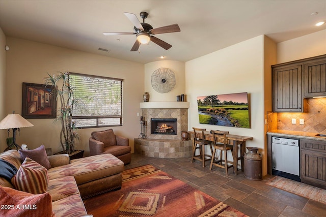 7731 E Soaring Eagle Way, Scottsdale, AZ 85266 - living room featuring stone tile flooring, a ceiling fan, a tiled fireplace, and recessed lighting