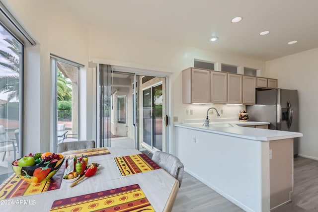 kitchen featuring sink, stainless steel fridge, kitchen peninsula, and light wood-type flooring