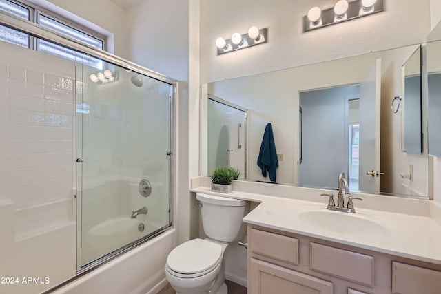 full bathroom with enclosed tub / shower combo, vanity, and toilet