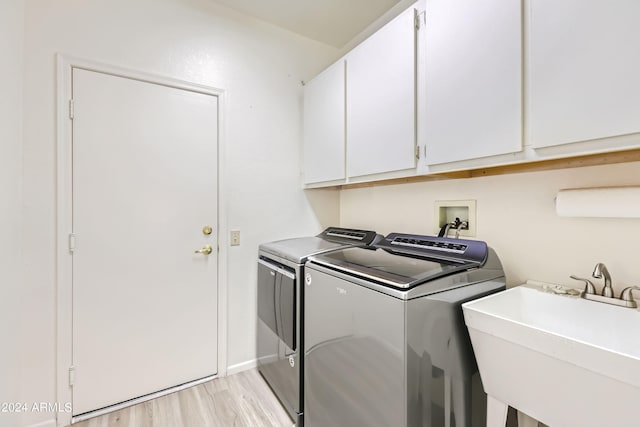 laundry room with light wood-type flooring, cabinets, separate washer and dryer, and sink